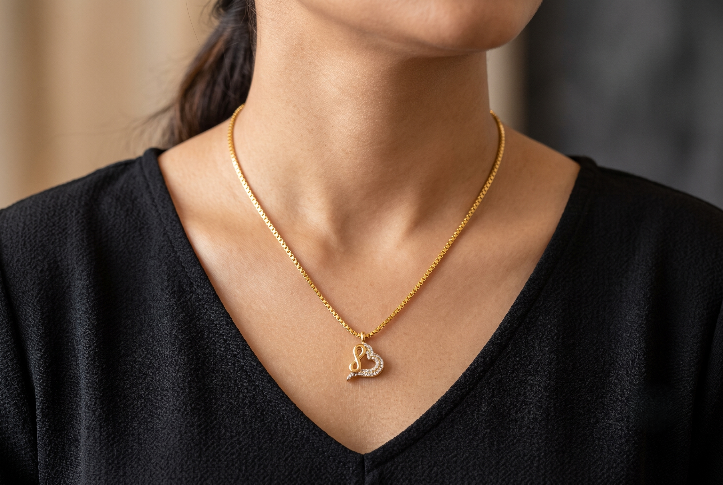 infinity-heart-pendant-chain-set model Rajyan Jewellers 18K gold Infinite Heart pendant and box chain lying on a luxury black velvet background