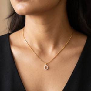 A woman wearing a 16 inch Rajyan Jewellers 18K yellow gold drop pendant necklace on the collarbone